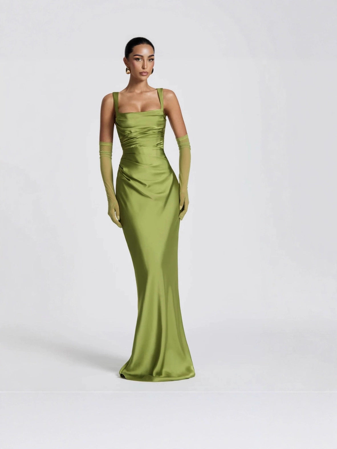Woman wearing a green evening gown and gloves on a white background